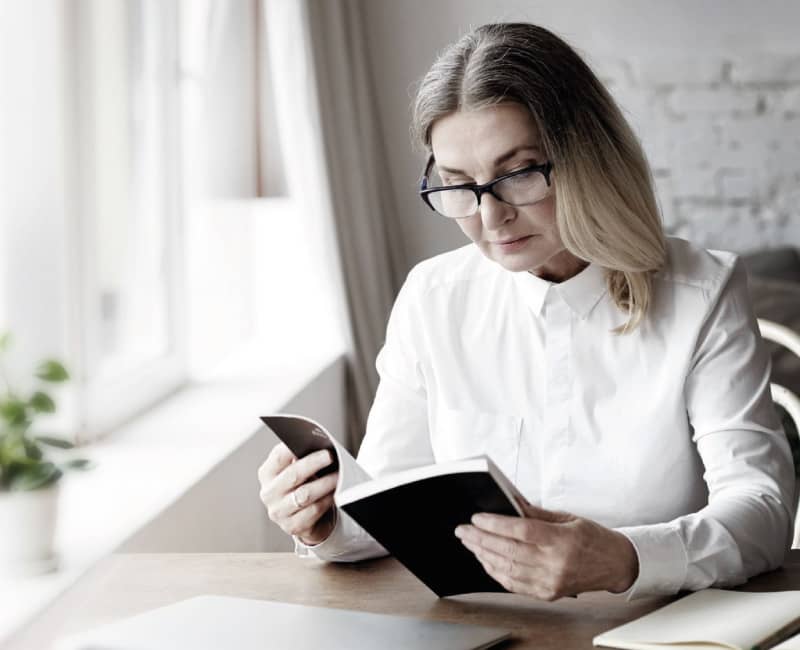 Mujer leyendo un libro usando lentes multifocales progresivos comprados en Ópticas David